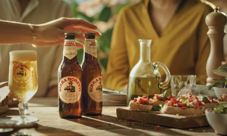 Birra Moretti in glas en flesjes met Italiaanse hapjes op tafel